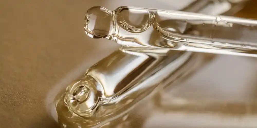 Transparent glass pipette lying on a golden background.